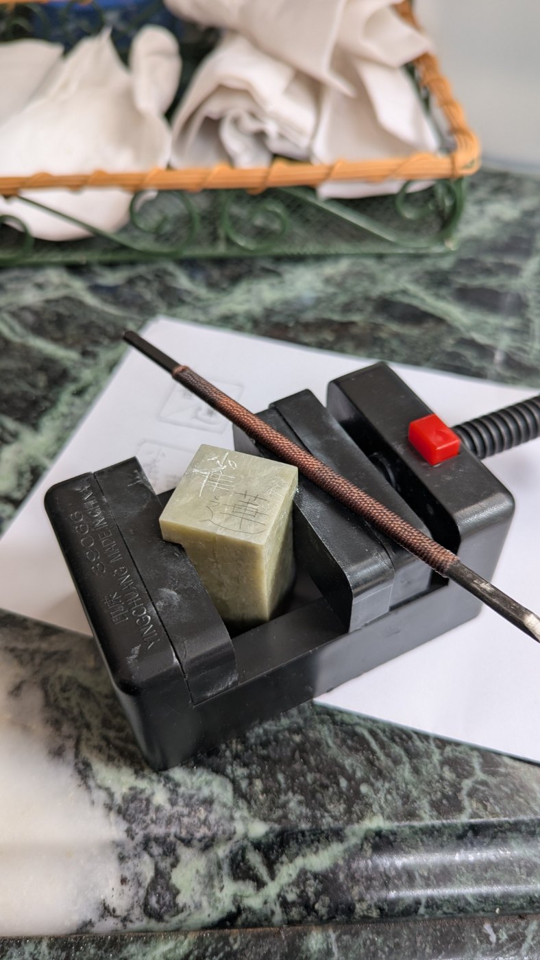 Hanko stone carved with the characters 雀蓮 for Jacqueline, held in a carving vise