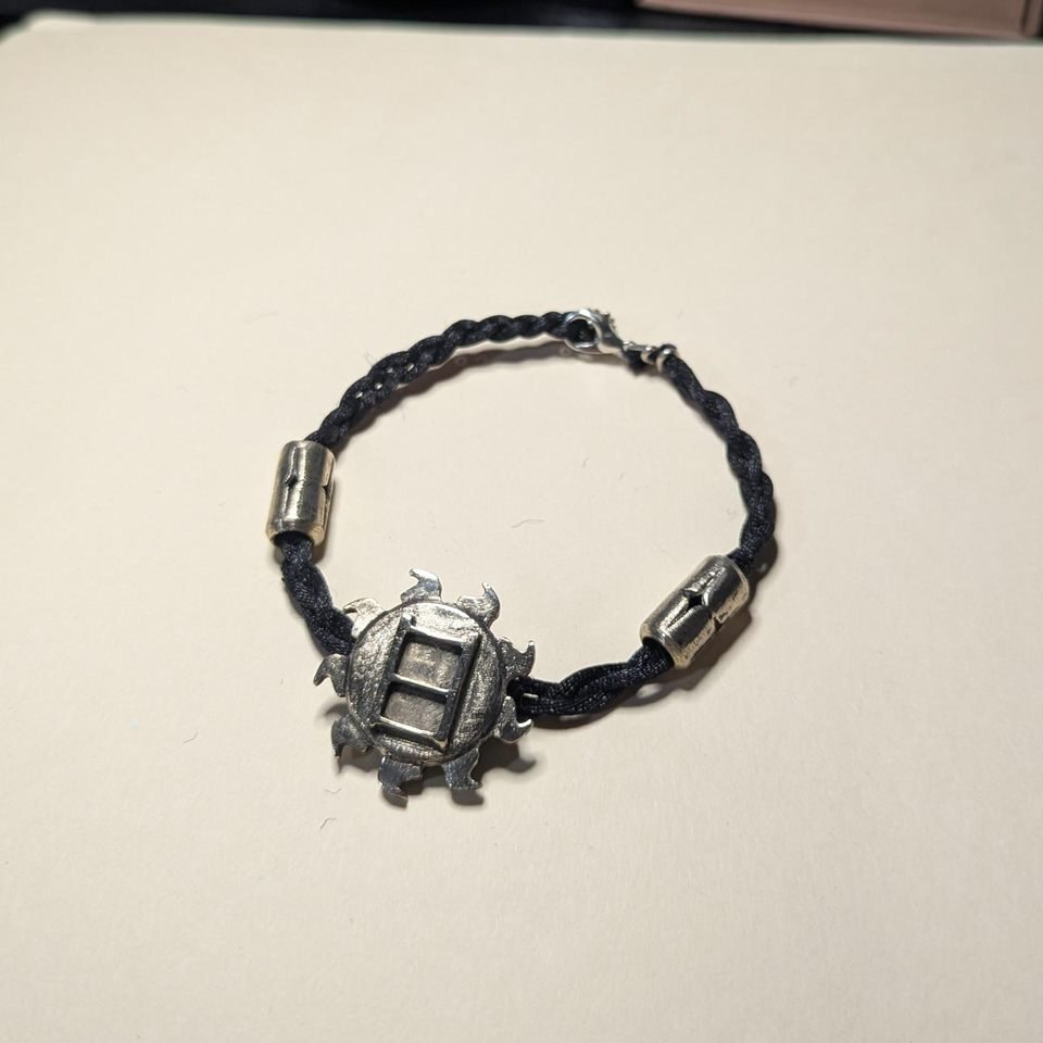 Sun Bracelet: a cast silver sun medallion on a braided black cord with silver barrel beads