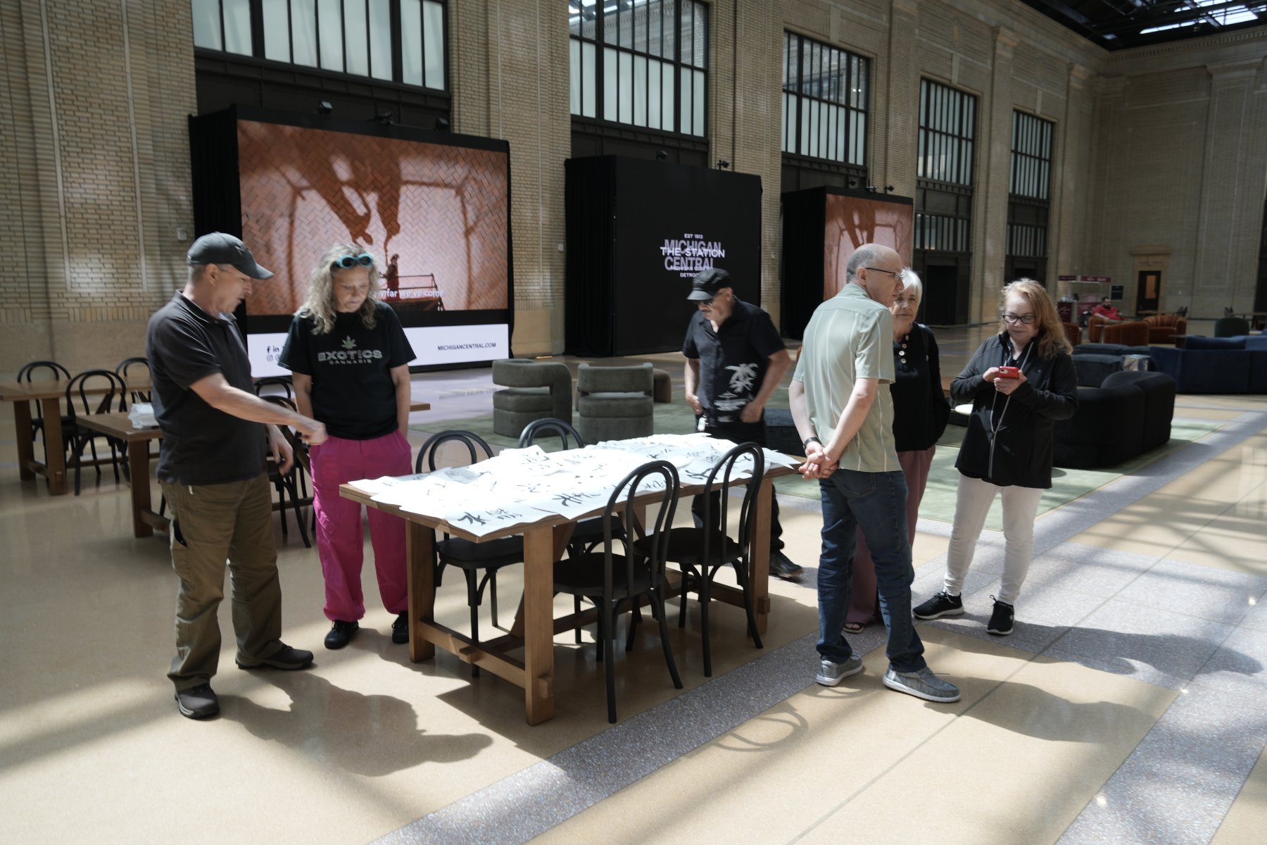 Visitors gathered around a table covered in the class's finished calligraphy sheets