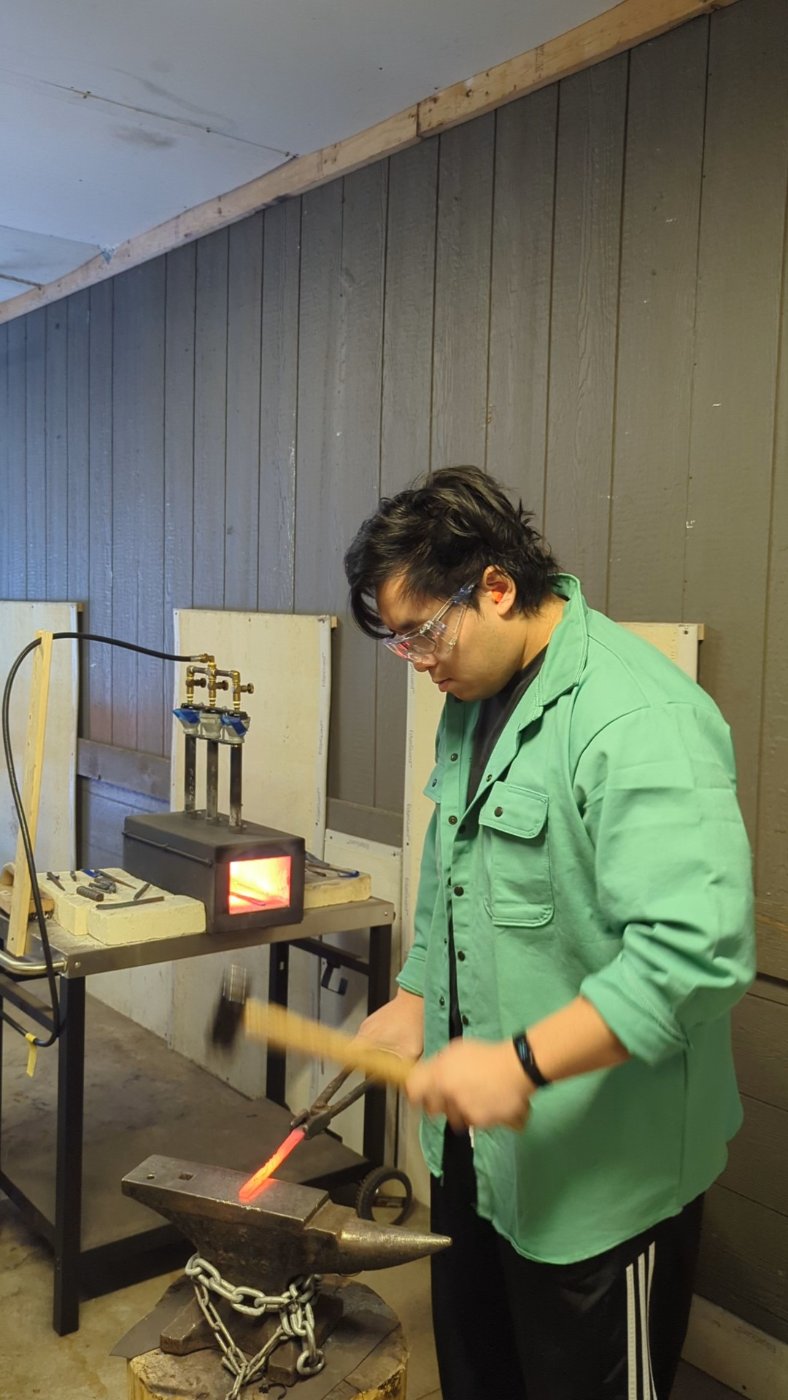 Skyler hammering glowing steel on an anvil at a forge