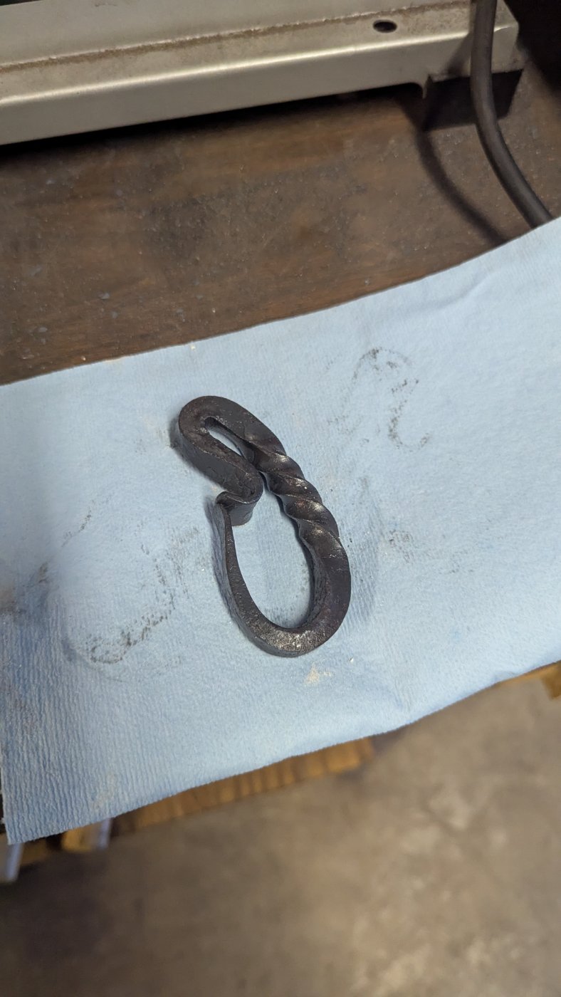 A hand-forged twisted iron hook resting on cloth
