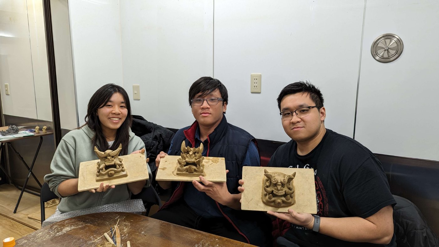 Three makers holding their finished clay onigawara guardian tiles