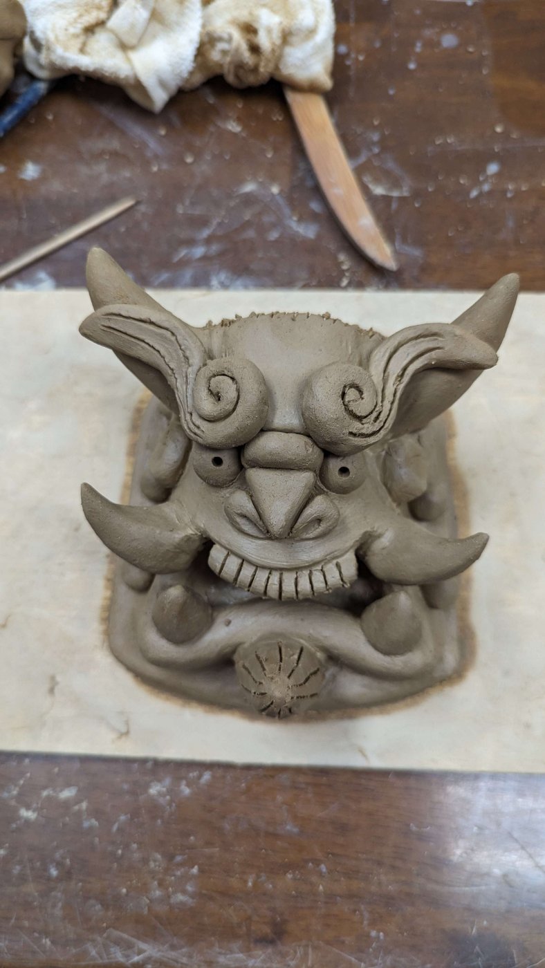 Close-up of a hand-sculpted clay onigawara demon-face tile