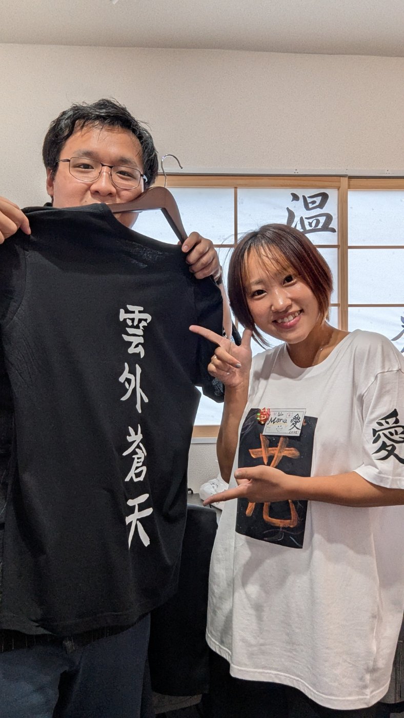 Skyler with Mana in Asakusa, holding a black shirt brushed with 雲外蒼天