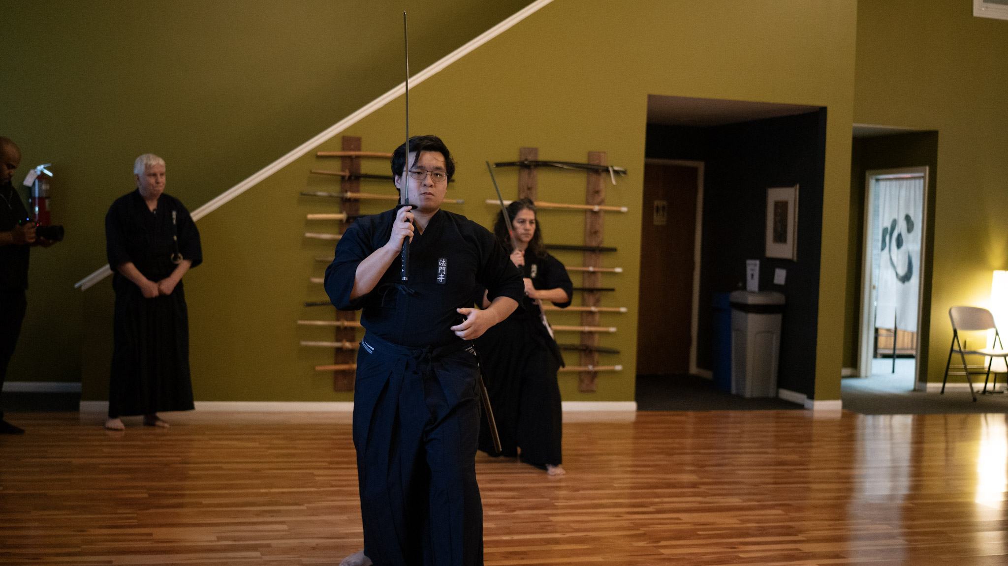 Iaido practitioner with an elder sensei holding katana in a dojo