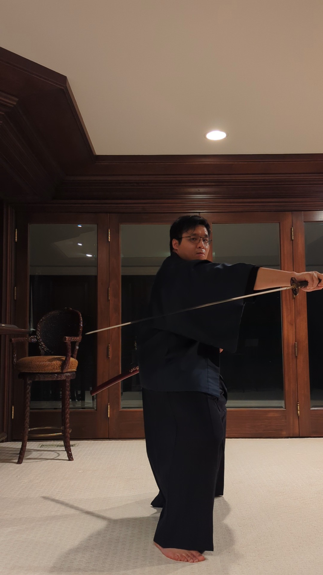 Iaido form drawing the blade across the body in a wood-paneled room