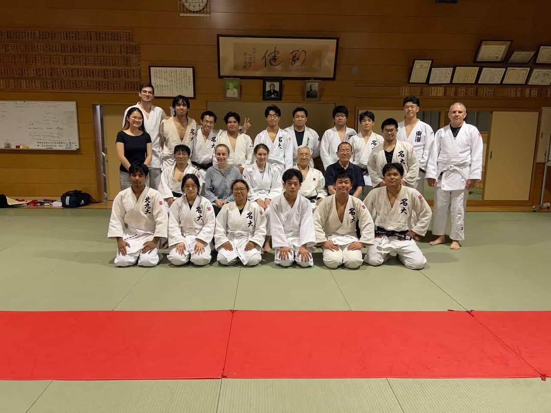 Judo club group photo on the tatami beneath calligraphy
