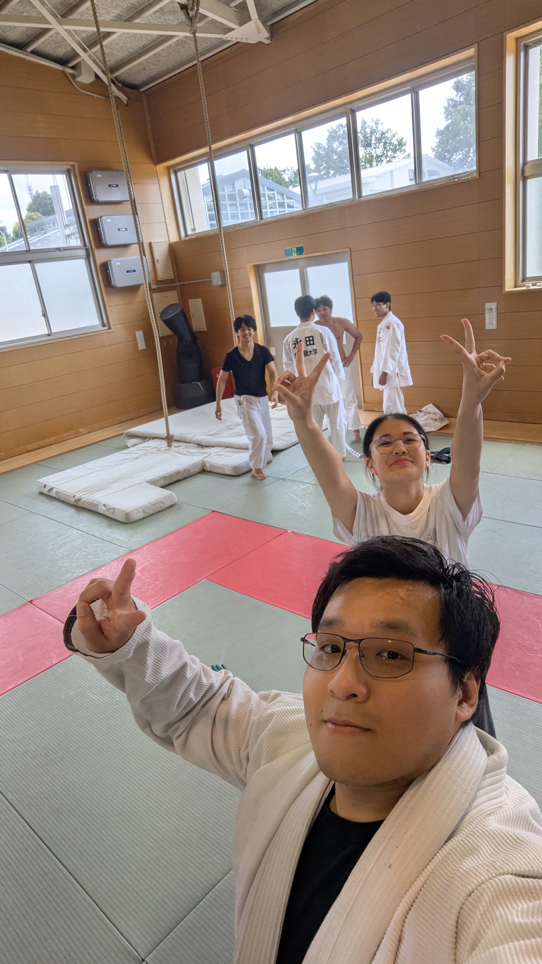 Judo dojo group on red and green tatami giving peace signs