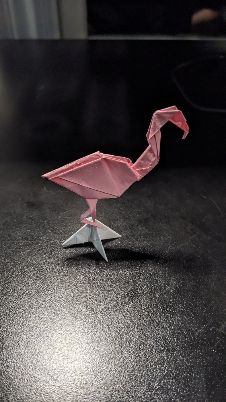 Pink origami flamingo on a stand