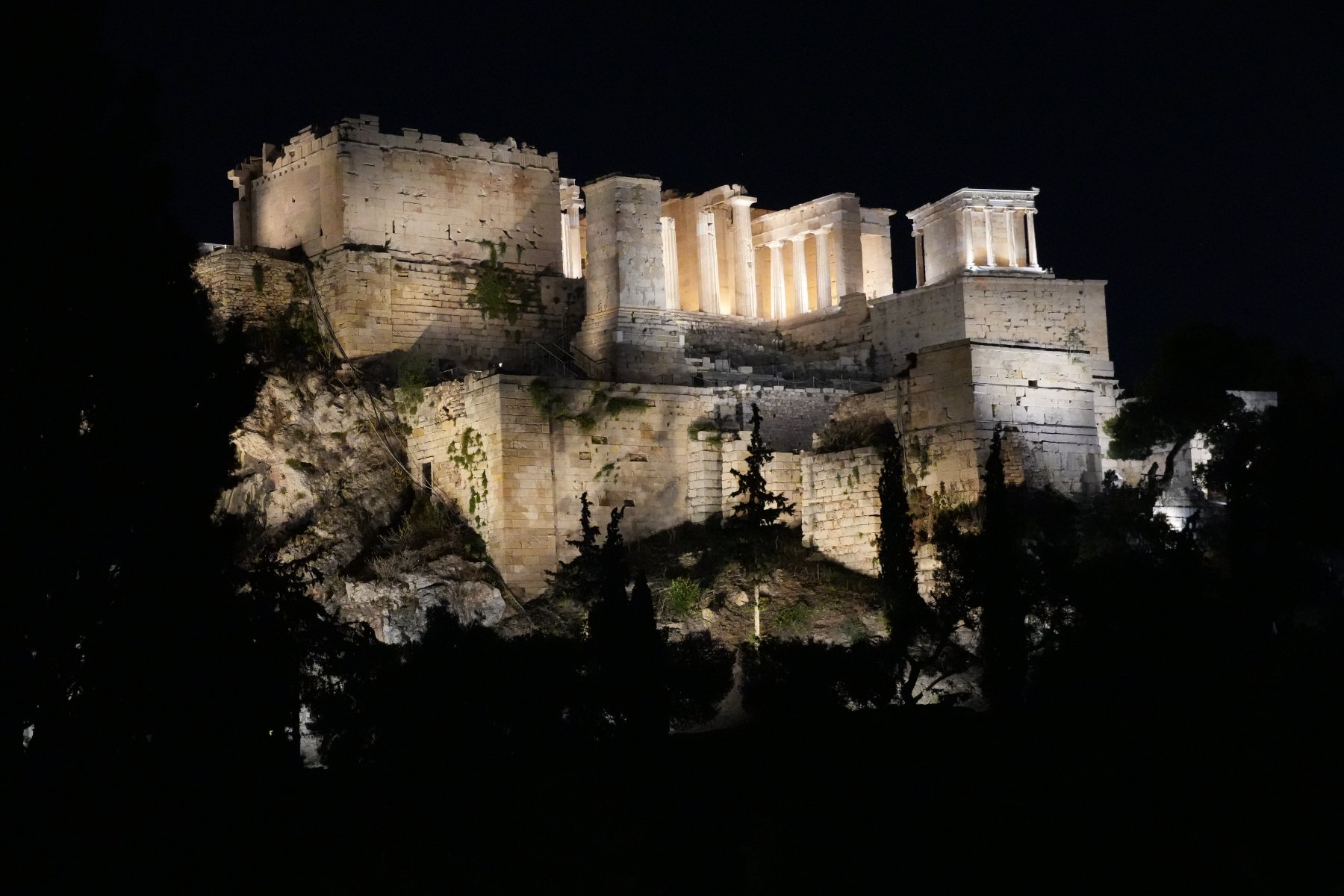 The Acropolis propylaea and Temple of Athena Nike floodlit against a black night sky, Athens