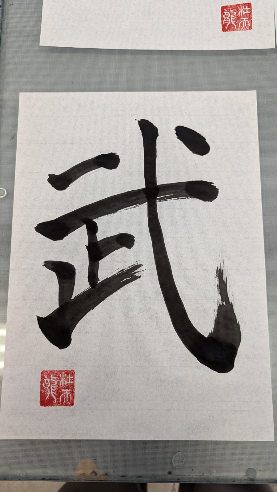 Shodo calligraphy of the kanji 武 (bu, martial) in bold black brushwork with a red seal