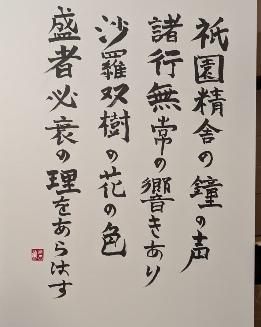 Shodo of the Heike Monogatari opening verse: 祇園精舎の鐘の声… brushed in four vertical columns with a red seal, framed and hung at the BBAC gallery