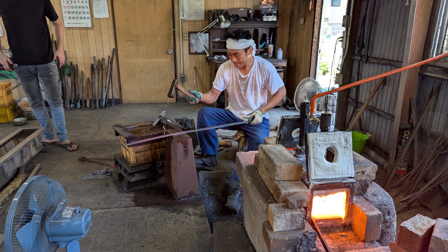 The smith quenching the heated blade in the long water trough